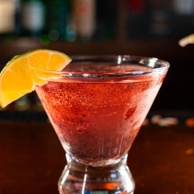 Cosmopolitan cocktail in a stemless martini glass with lime garnish