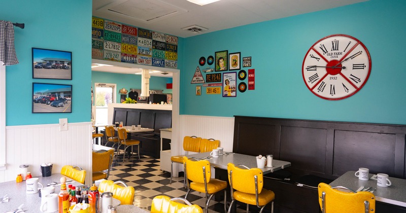 Interior of a diner with turquoise walls, vintage clock, and yellow chairs