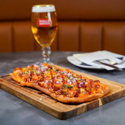BBQ chicken flatbread accompanied by a glass of beer.