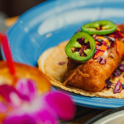 Cod taco with cabbage and jalapenos on a blue plate.