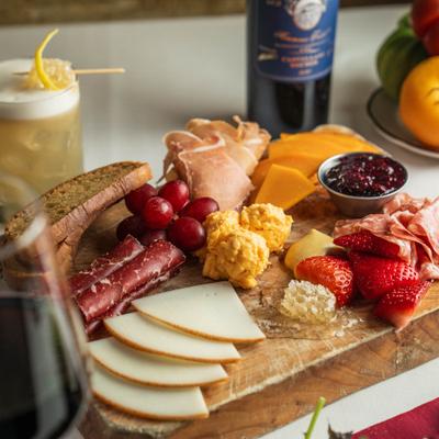 Antipasto board with assorted  meats, cheeses, fresh fruits, brad, jam, and honeycomb.