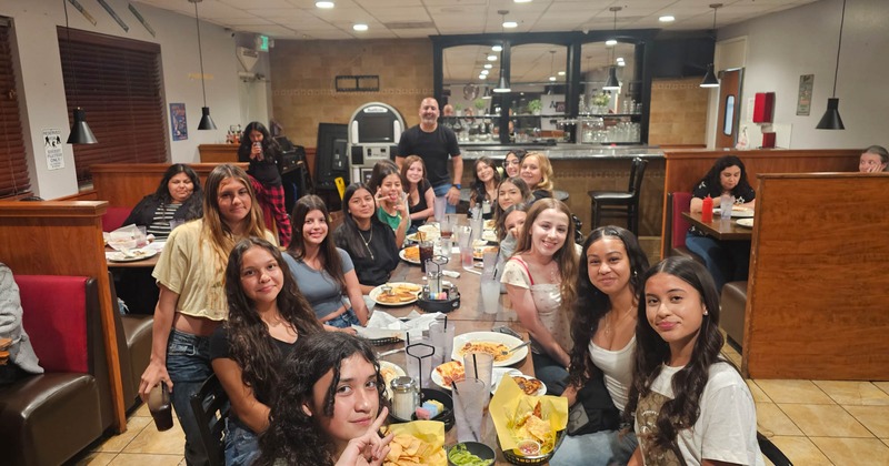 A group of people gathered around a table, posing for picture in dining area