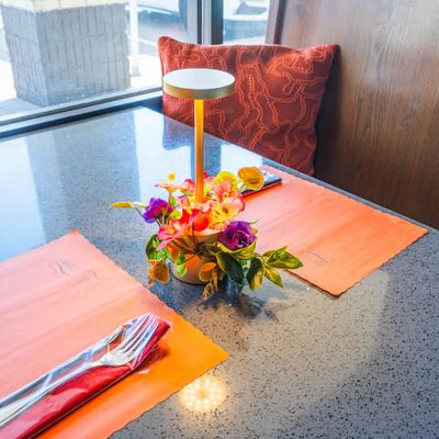 Tabbe setting with mats, cutlery and a table tamp with flower arrangement.