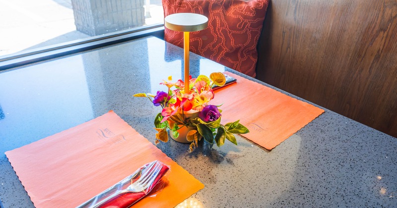 Table setting with mats, cutlery and arrangement of flowers with a lamp