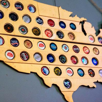 The wooden USA map on the wall with bottle caps embedded in it.