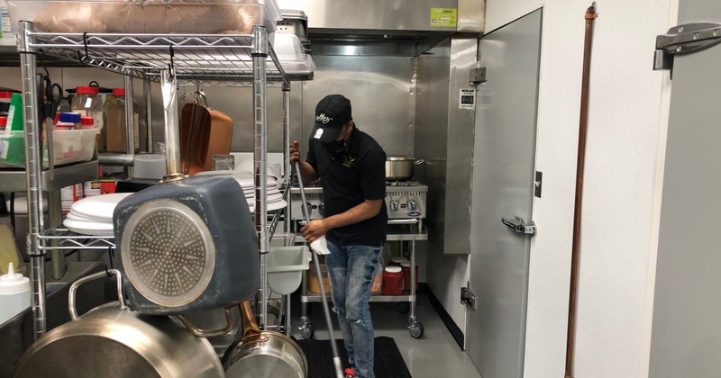 Staff member cleaning the floor in the kitchen