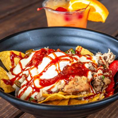 Nachos, with pork, melted cheese, sauce, and veggies.