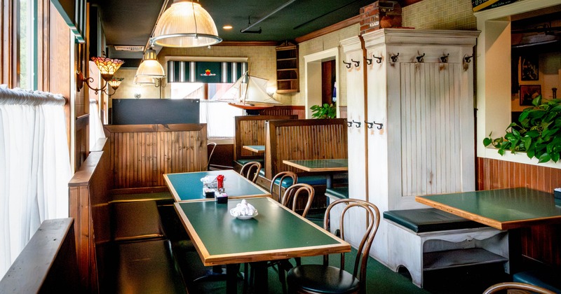 Interior, wooden booths, dark green tables, hanging lamps, and decorative elements