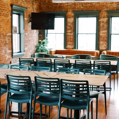 Dining room with teal chairs, brick walls, and marble tables.