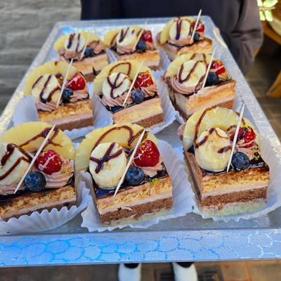 Dessert cake squares topped with tropical fruits displayed on a tray.