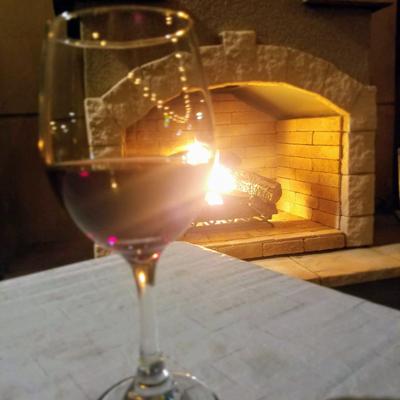A glass of wine on a table with a cozy fireplace in background.