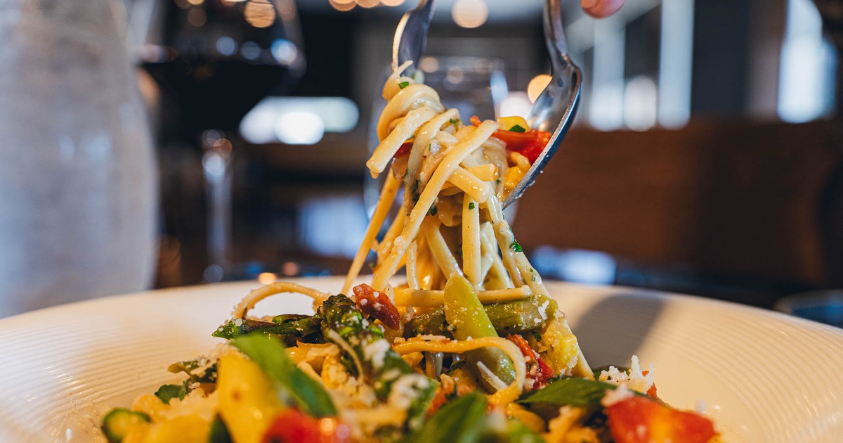 Restaurant table with black plates and silver cutlery, striped booth