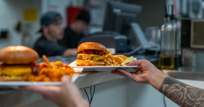 A waitperson with ordered burgers on plates