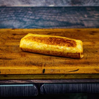 A burrito served on a wooden board.