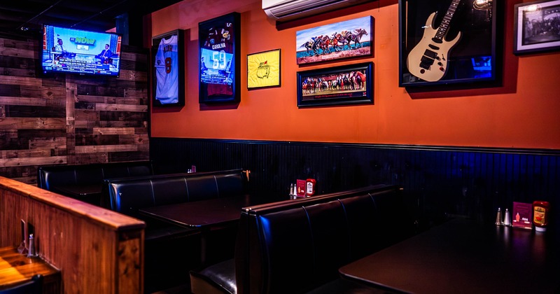 Interior of a restaurant with black leather booths, sports memorabilia on the walls