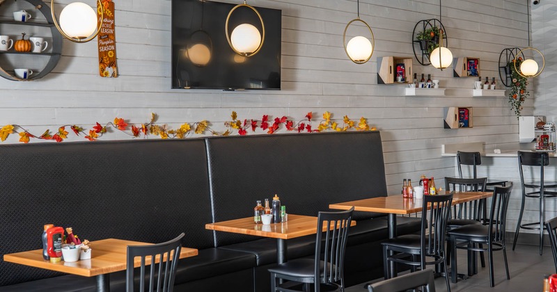 Interior, banquette seating and tables by a wall, TV on the wall