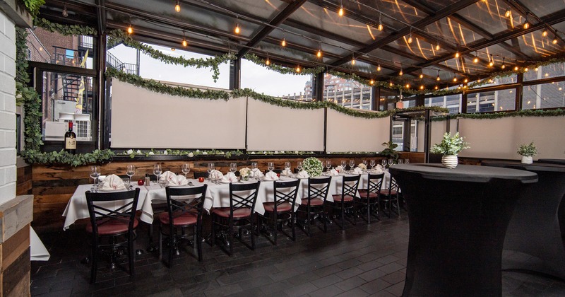 An elegant dining setup in an enclosed patio space, with a set banquet-style table