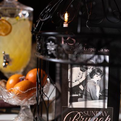 A dimly lit scene with a vintage-style Sunday Brunch sign inside a decorative black cage.