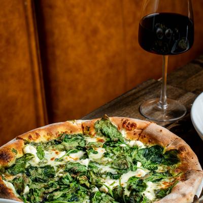 Florentine pizza with spinach accompanied by a glass of red wine.