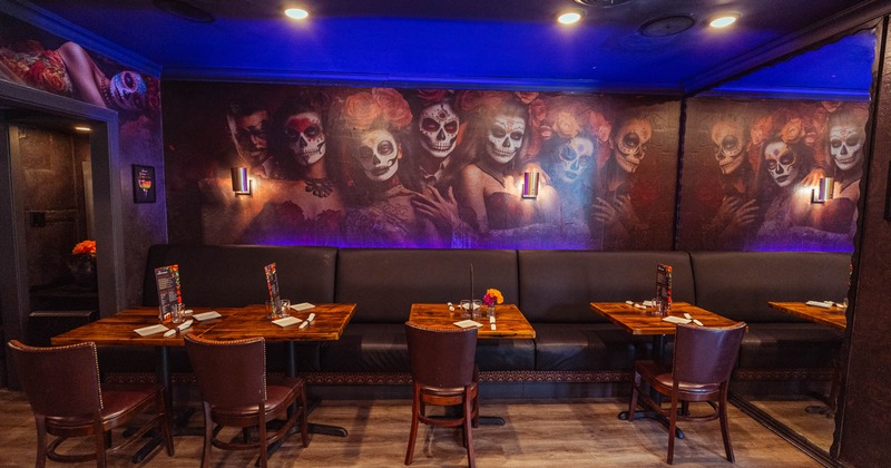 A restaurant interior with Day of the Dead-themed mural and wooden tables