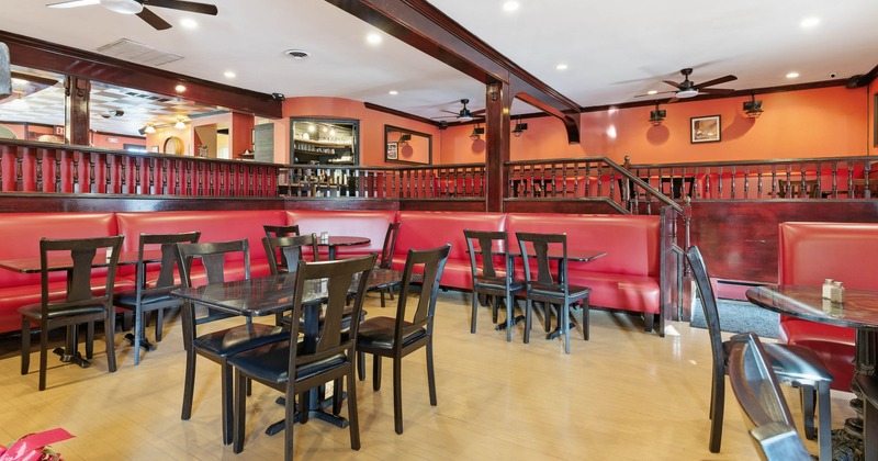 Restaurant interior with wooden floors, red booths and dark wood furniture.