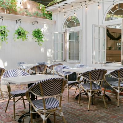 Outdoor patio with striped chairs, brick flooring, hanging plants, and string lights