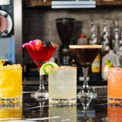 Assorted cocktail lined up on a bar counter.