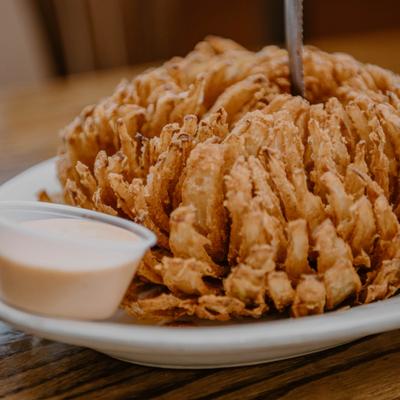 Blooming onion served with a dipping sauce.