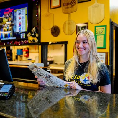 A friendly employee standing behind a counter with a POS system.