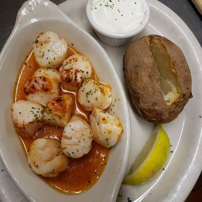 Scallops, in sauce, served with a baked potato, and dip.