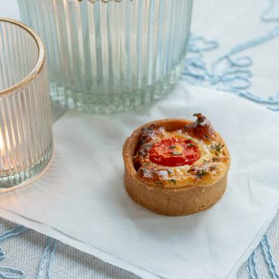 Tomato pie placed on a table with glass candle holders , close up.