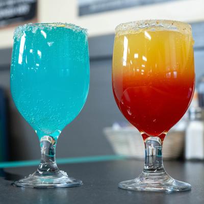 Two colorful cocktails served in rimmed goblets.