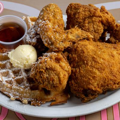 Chicken and Waffles topped with powdered sugar and served with syrup and butter.