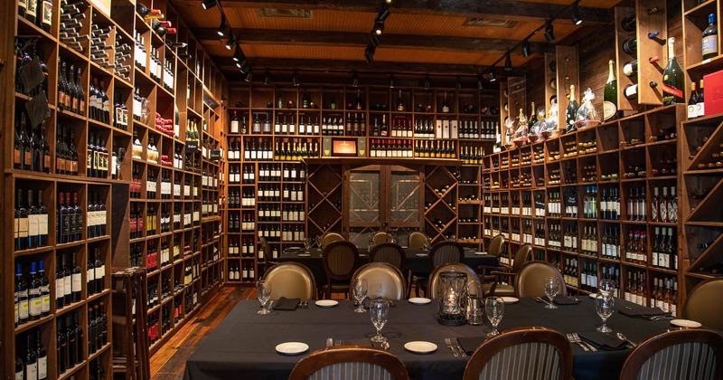 Lots of bottles on the shelf, tables ready for guests