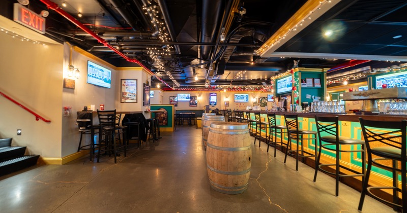 Interior of a cozy sports bar with a large bar and wooden barrels as standing tables