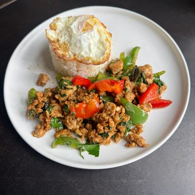 Stir-fried minced meat, red and green bell peppers, and fresh herbs, rice topped with a fried egg.