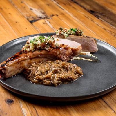 Iberian Duroc Pork Chop on a black plate with savory sauce.