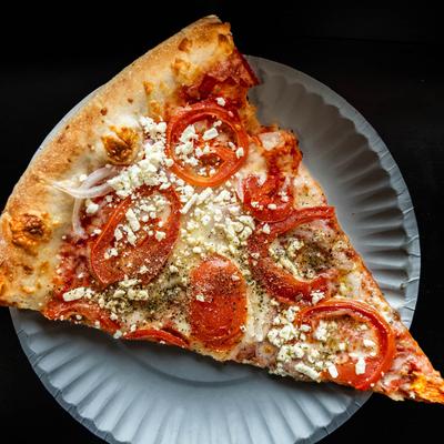 A slice of pizza with tomatoes, onions, and feta cheese.