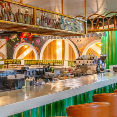 Bar area with a counter, stools and a metal mesh bottle rack hanging over the bar.