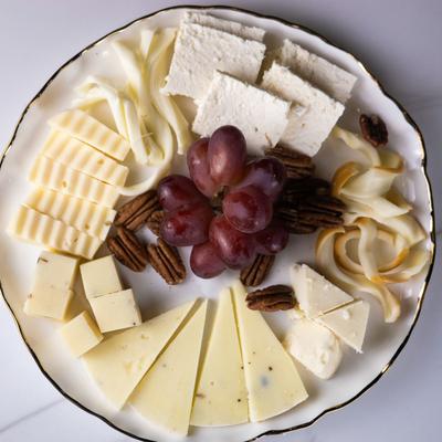 Cheese platter with various cheeses, pecans, and red grapes.