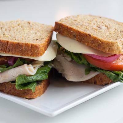 Sandwich with bacon, turkey ham, cheese, tomato, lettuce and red onion