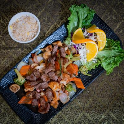 Steak and shrimp with vegetables and a side of rice, top view.
