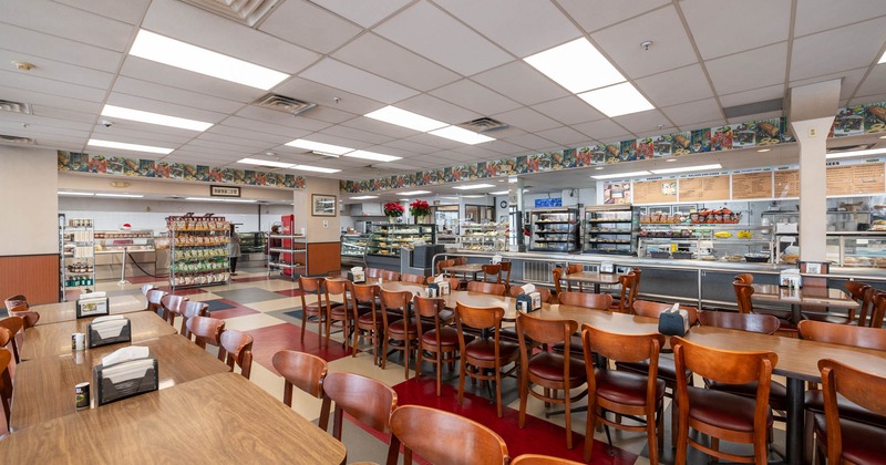 Interior, long table dining setups with chairs, refrigerated display cases