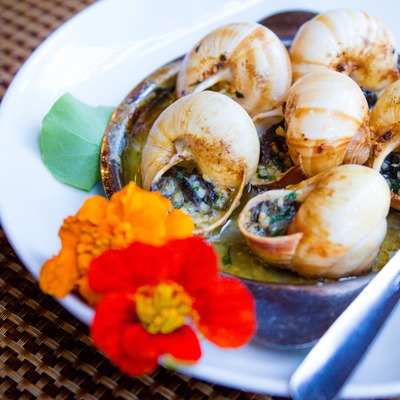 Escargot cooked in herb butter, served in shells with flowers.