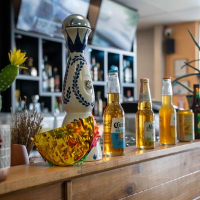 Various bottles of beer served on the bar counter alongside a bottle of tequila.
