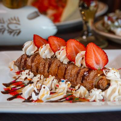 Cheesecake Chimichanga with whipped cream, strawberries, and syrups.