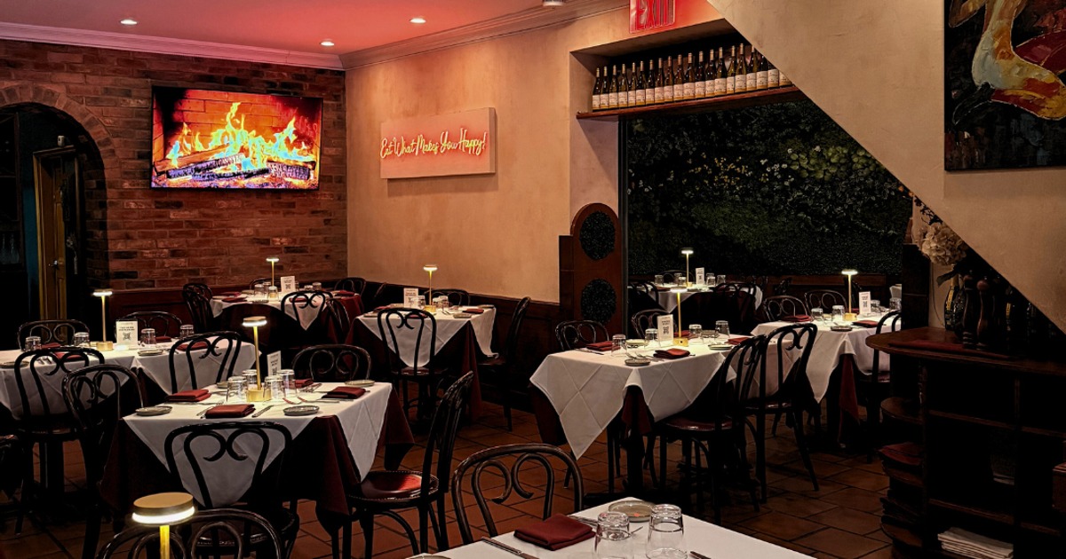 Elegant dining room with a fireplace display on a brick wall and set tables