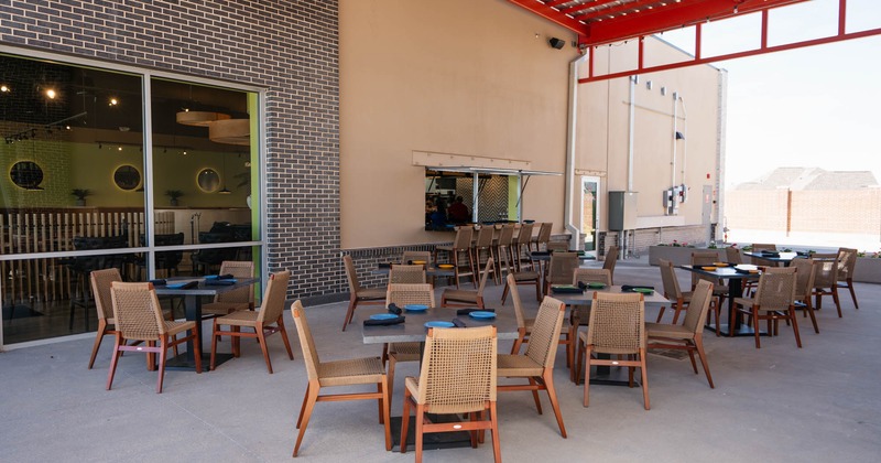 Exterior, covered seating area, tables with chairs ready for guests, concrete flooring