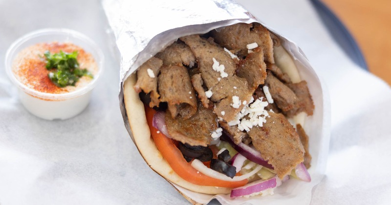Lamb gyro wrap served with a dipping sauce on the side