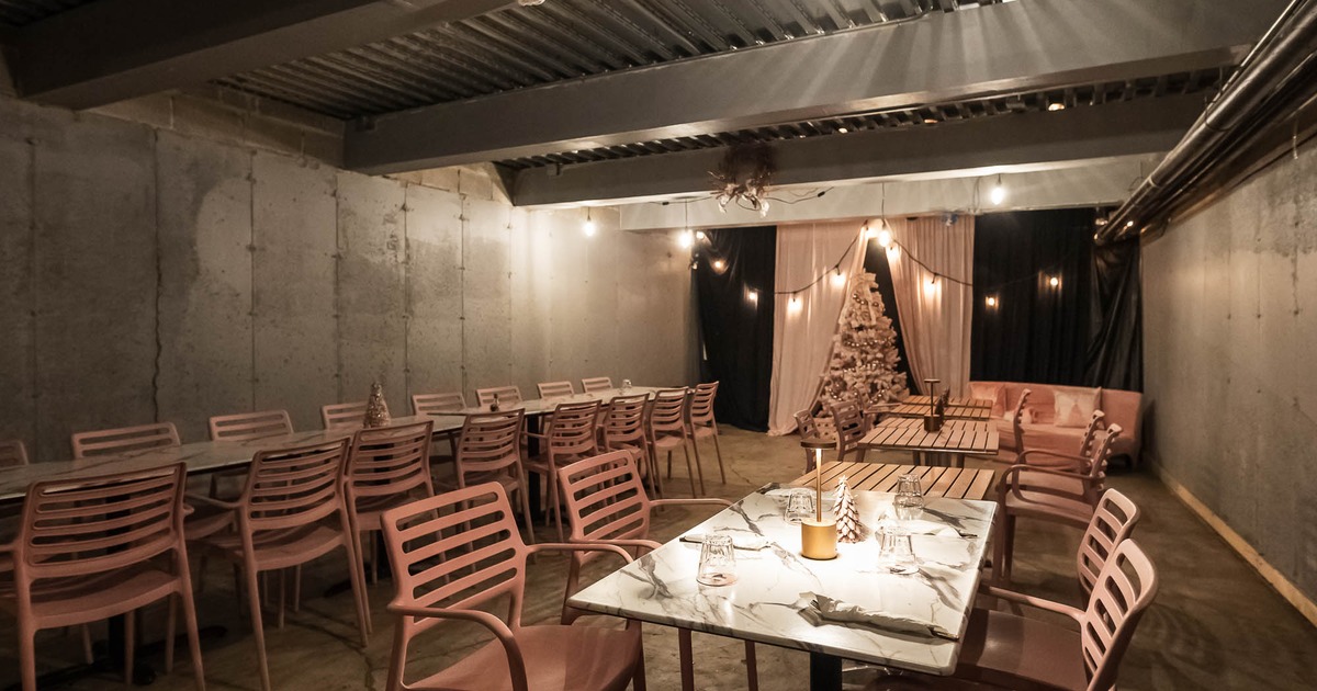 Dining area with tables, chairs, string lights, and a Christmas tree